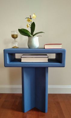 a blue table with books and a vase on top