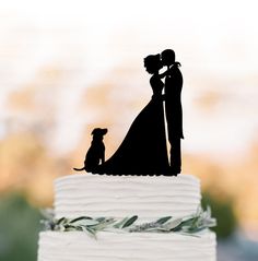 a wedding cake topper with a silhouette of a bride and groom standing next to their dog