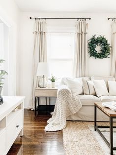 a living room with white furniture and curtains