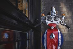 a red, white and blue motorcycle parked in front of a building next to a brick wall