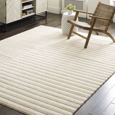 a large white rug in a living room next to a wooden chair and book shelf