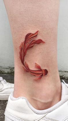 a woman's foot with a small red fish tattoo on the side of her leg