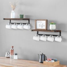 two wooden shelves with coffee mugs and cups hanging on the wall next to each other