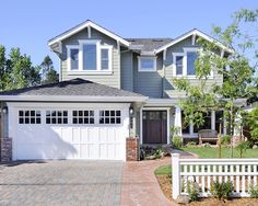 a large house with two garages and a white picket fence in front of it