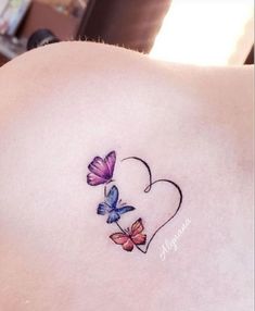 the back of a woman's shoulder with two butterflies on it and a heart