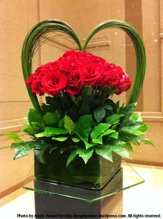 a heart shaped vase filled with red roses