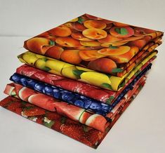 a stack of fruit printed napkins on top of each other in different colors and patterns