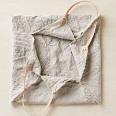 a piece of cloth is tied up to a string on a table with a white background