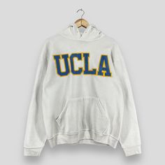 "REMINDER: THIS IS USED CLOTHING PLEASE DO NOT EXPECTED IT LIKE TO BE NEW OR IN PRISTINE CONDITION Feel free to contact me for any question. I'll assist you with my pleasure. Vintage UCLA Pullover Hoodie Large 1990's University Of California Spellout Embroidery Sportswear Sweater Ucla White Hoodie Sweater Size L *All measurements are taken with the garment flat on the ground. SIZE ON TAG :- Size L ACTUAL SIZE MEASUREMENT :- ARM PIT TO ARM PIT :- 23\" inches BACK COLLAR TO HEM :- 26\" inches CONDITION :- GREAT USED CONDITION. NO HOLES AND STAINS. ** WE ARE USING DHL EXPRESS, IT TAKES 3-5 WORKING DAYS ONLY TO ARRIVE. PLEASE LEAVE YOUR PHONE NUMBER ON THE NOTE WHILE MAKE A PURCHASE** REF : (13-01-2021) 888" Collegiate Hooded Tops For College, Oversized Hoodie For College, Sports Hooded Top With Embroidered Logo, Vintage Hoodie With Double-lined Hood For Sports, Throwback College Hoodie For Fall, Throwback Fall Hoodie For College, Throwback Hooded Top For College, Oversized Vintage Hooded Hoodie, Vintage College Sweatshirt With Embroidered Logo