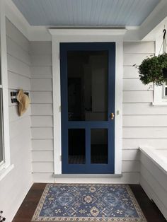 a blue front door on the side of a house with a rug and potted plant