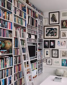 there is a ladder in front of the bookshelf full of books and pictures