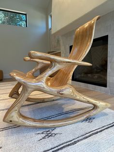 a wooden rocking chair sitting on top of a rug in front of a fire place