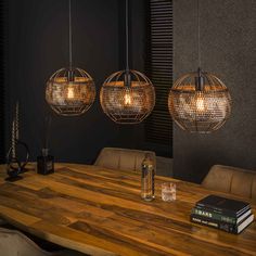 three lights hanging over a wooden table in a dark room with two books on it