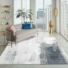 a living room filled with furniture and large windows next to a white rug covered in blue and pink pillows