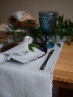 the table is set with white linens and silverware, along with greenery