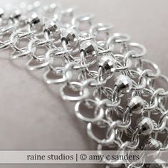 a close up view of a silver chain on a white background with the words raine studios @ any e - sandlers