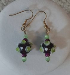 This pair of earrings is made with lime green spotted purple baubles, lime green cat's eye beads, and purple seed beads. Silver-plated earring hooks and wire were used. Green Czech Glass Earrings With Colorful Beads, Christmas Tree Necklace, Blue Beaded Earrings, Whale Necklace, Tree Necklace, Eye Beads, Themed Jewelry, Earring Hooks, Beaded Earrings