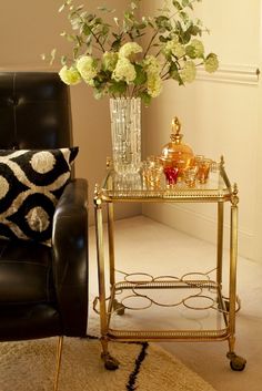 a vase with flowers on a table next to a black leather chair in a living room