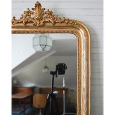 an ornate gold framed mirror in the corner of a room with a camera and tripod