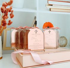 three small bottles with labels on them are sitting on a table next to some flowers