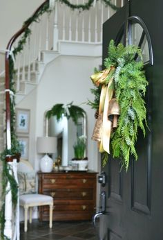 a christmas wreath on the front door of a house with bells hanging from it's side