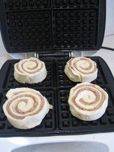 three cinnamon roll waffles sitting on top of a black pan