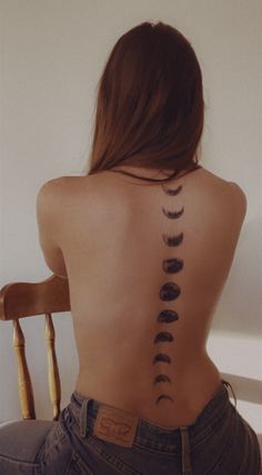 a woman sitting in a chair with her back turned to the camera and tattoos on her lower back