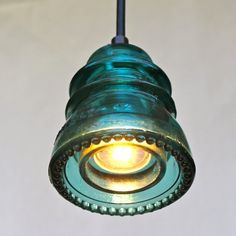 a green light hanging from a ceiling with a white wall in the backround