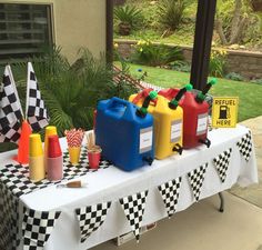 a table topped with plastic jugs filled with different colored liquids and cups on top of it