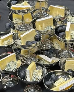 a table topped with lots of trays filled with cheese and blueberries on top of each other