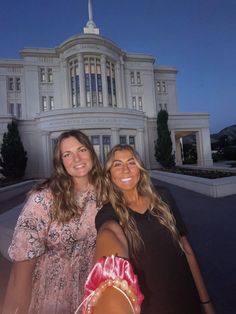 two women standing in front of a large building