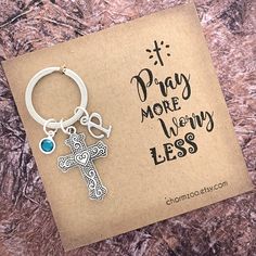 a keychain with a cross on it and the words pray more worry less