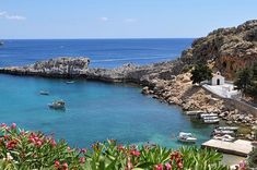 boats are docked in the blue water near some cliffs