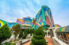 an amusement park with colorful buildings and trees in the foreground, on a sunny day