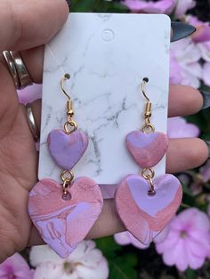 pink and purple heart shaped earrings with gold hooks on marble slabd earwires