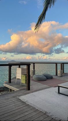 a wooden dock with two lounge chairs and a palm tree