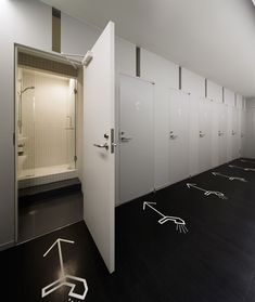 an empty bathroom with white walls and black flooring is decorated with drawings on the wall