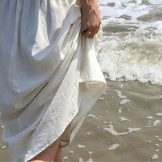 a person standing on top of a beach next to the ocean holding a white towel