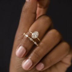 a woman's hand holding an engagement ring with two diamonds on it and the other hand