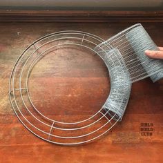 a person holding a piece of wire on top of a wooden table