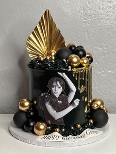 a black and gold birthday cake with an image of a woman on it