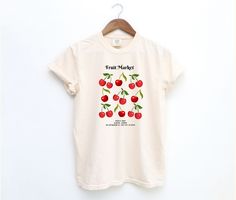 Celebrate the vibrant charm of a local fruit market with our "Fruit Market" Event T-Shirt. Featuring a delightful illustration of cherries, this design includes the event details above and below the artwork. The text reads "Fruit Market" above and "02 July, 2024 | 8:30am - 3:00pm | 123 Anywhere St., Any City, ST 12345" below. Crafted from high-quality 100% ring-spun US cotton, this Comfort Colors 1717 tee offers a relaxed fit perfect for casual and semi-formal settings. The medium-weight fabric ensures long-lasting comfort and durability, while the garment-dyed finish provides a soft, vintage look and feel. Pre-shrunk for a consistently great fit, this t-shirt is ideal for anyone looking to commemorate a special event or simply enjoy a stylish, comfortable tee. Key Features: -100% Ring-Spu Organic Short Sleeve T-shirt For Spring, Cherry Short Sleeve Tops For Summer, Organic White T-shirt For Summer, Red Short Sleeve T-shirt With Fruit Print, Organic Graphic Print T-shirt For Spring, Spring Fruit Design Short Sleeve Tops, Spring Organic White T-shirt, Organic Graphic Print Top For Spring, Organic Tops With Graphic Print For Spring