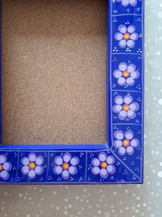 a blue frame with flowers painted on the side and dots in the bottom, sitting on a table