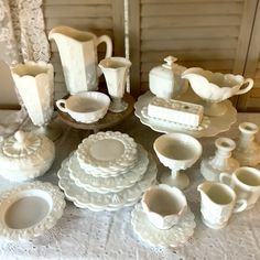 a table topped with lots of white dishes and cups