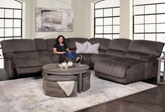 a woman sitting on a couch in front of a large sectional sofa with recliners