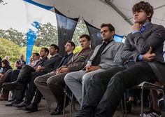 a group of men sitting next to each other in front of a crowd