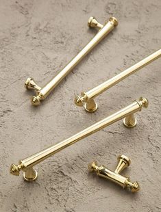 three brass handles and four knobs on a gray surface with sand behind them in the foreground