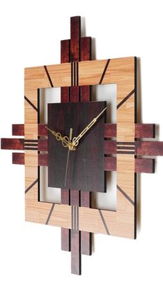 a clock made out of wood and metal on a white background with gold hands, in the shape of a square