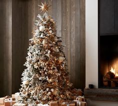 a christmas tree with presents under it in front of a fire place and wooden wall