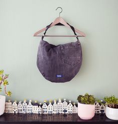 a purse hanging on a wall next to some potted plants and other things in front of it